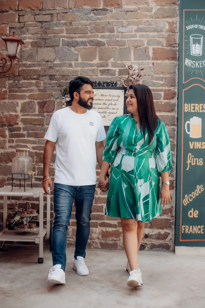 Couple walking together past a rustic brick wall during an outdoor pre-wedding shoot
