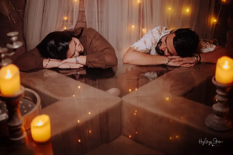 Couple resting close together surrounded by candlelight and fairy lights