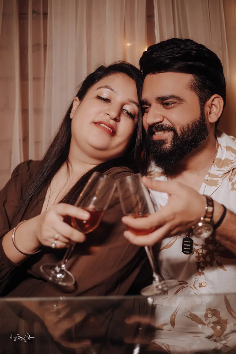 Couple sharing a glass of wine in warm candlelight during an evening pre-wedding shoot