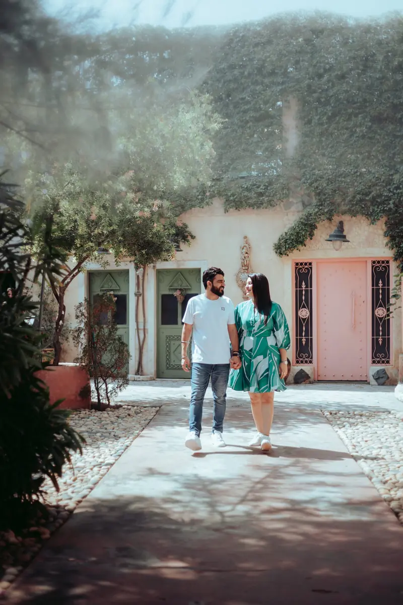 Couple walking hand in hand down a sunlit villa courtyard path