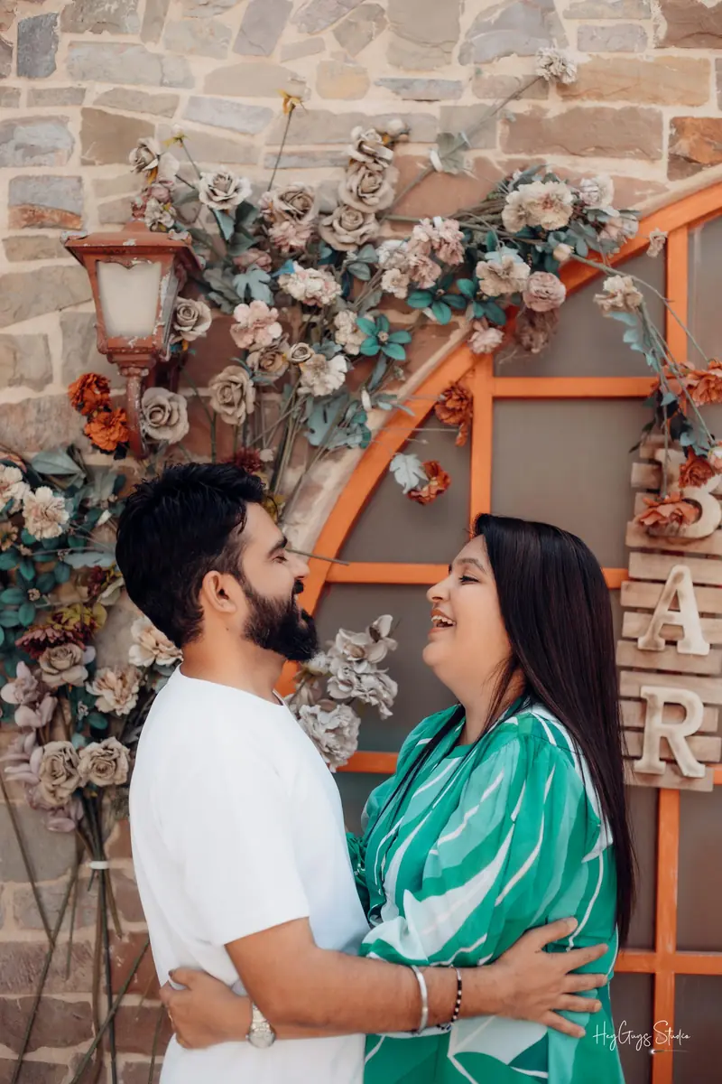 Couple embracing beneath a floral archway at a pre-wedding shoot location