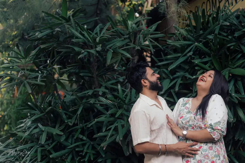Couple embracing against dense tropical greenery during an outdoor pre-wedding shoot