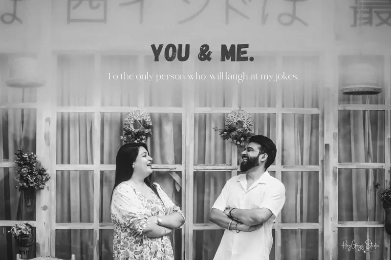 Black and white candid of a couple laughing outside a decorated storefront