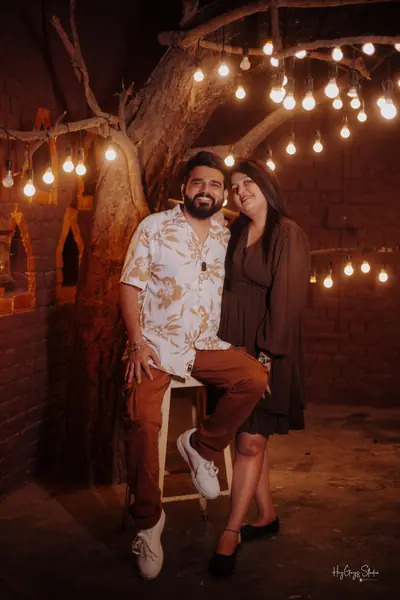 Couple standing beneath a tree strung with glowing fairy lights at dusk