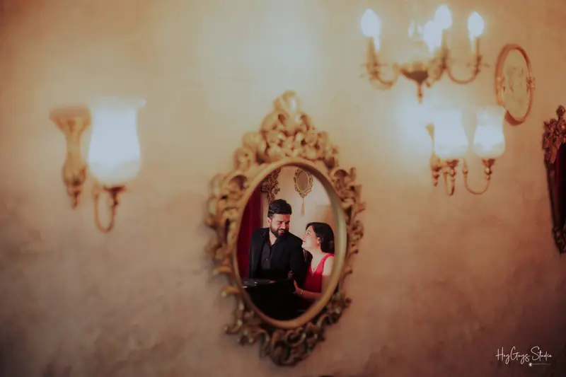 Couple reflected in a gilded mirror between warm wall chandeliers