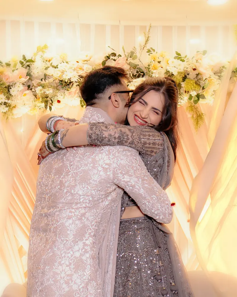 Bride and groom sharing a warm embrace in front of a floral wedding mandap